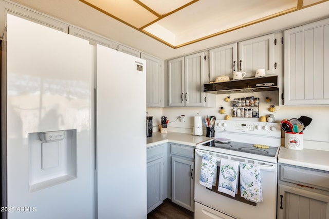 kitchen featuring white appliances, light countertops, under cabinet range hood, and gray cabinetry