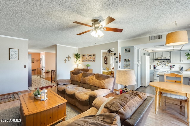 living room featuring ornamental molding, visible vents, and light wood-style floors