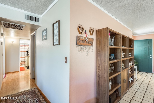 hallway featuring crown molding, visible vents, and a textured ceiling