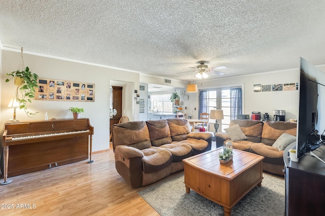 living area featuring a textured ceiling, ceiling fan, visible vents, light wood-style floors, and ornamental molding