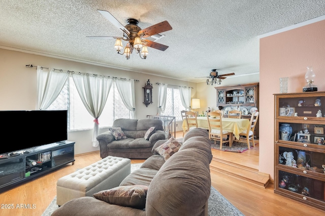 living area with ceiling fan, a textured ceiling, ornamental molding, and wood finished floors