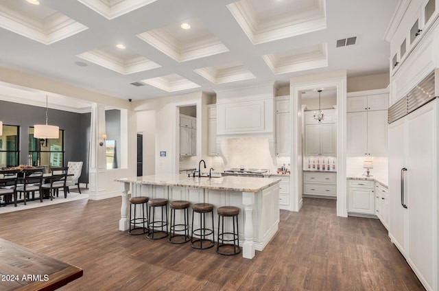 kitchen featuring decorative backsplash, white cabinetry, dark hardwood / wood-style flooring, and an island with sink