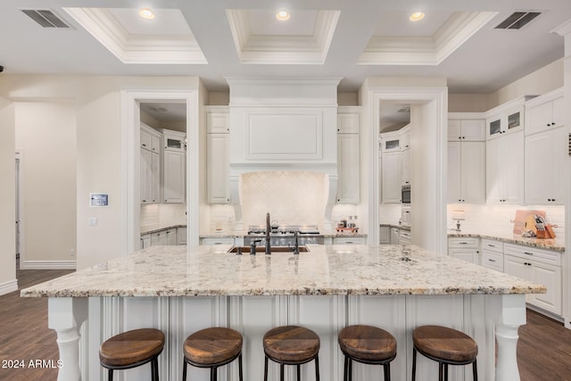 kitchen featuring dark hardwood / wood-style flooring, a spacious island, light stone counters, and coffered ceiling