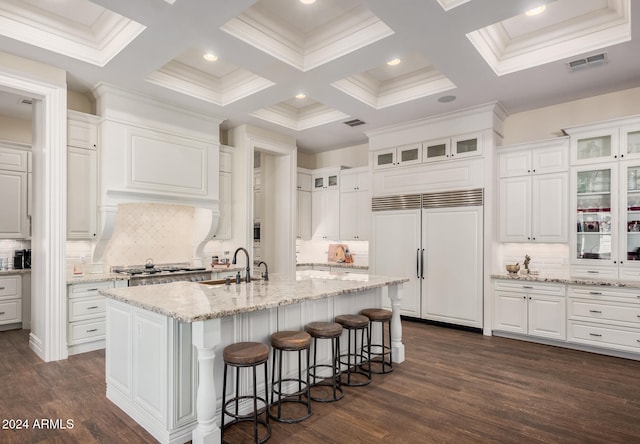 kitchen featuring white cabinets, dark hardwood / wood-style floors, paneled built in fridge, and a kitchen island with sink