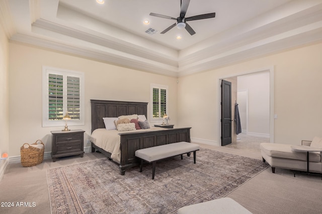 carpeted bedroom featuring ceiling fan, a tray ceiling, and multiple windows