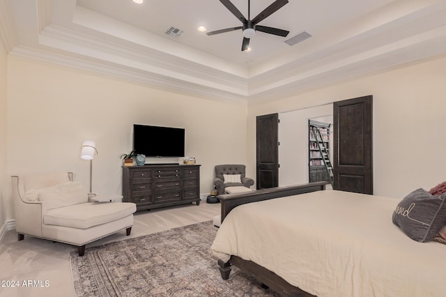 carpeted bedroom with ceiling fan, a raised ceiling, crown molding, and a high ceiling