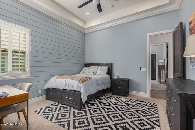 carpeted bedroom featuring a tray ceiling, ceiling fan, and wood walls