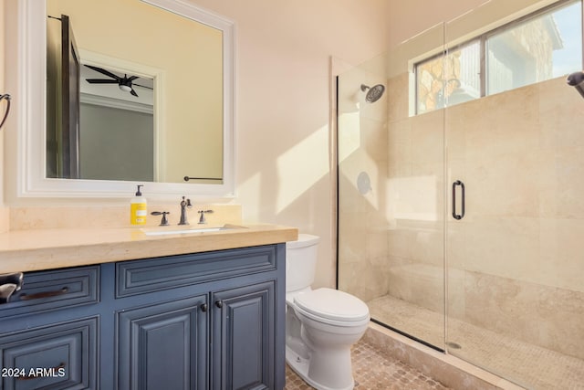 bathroom featuring vanity, toilet, ceiling fan, and a shower with shower door