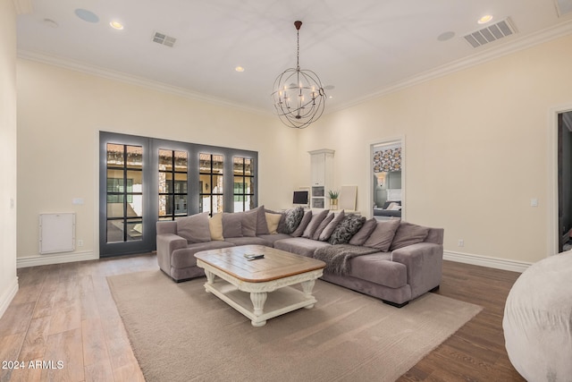 living room featuring hardwood / wood-style flooring, crown molding, and a notable chandelier