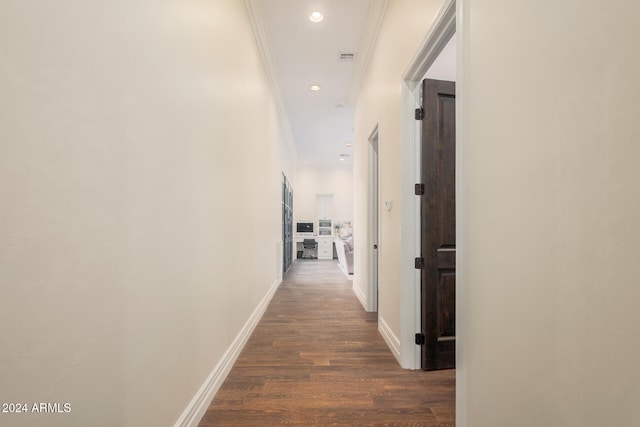 corridor featuring ornamental molding and dark wood-type flooring