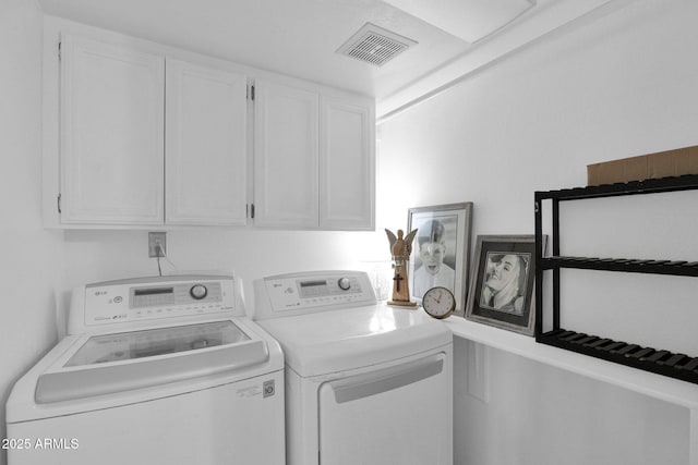 clothes washing area featuring washing machine and dryer and cabinets