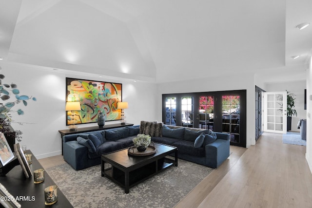 living room with hardwood / wood-style flooring, high vaulted ceiling, and french doors