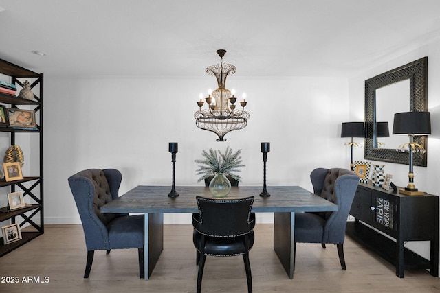 dining room with light wood-type flooring and an inviting chandelier