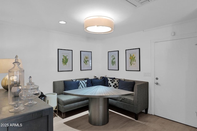 living room featuring breakfast area, wood-type flooring, and crown molding