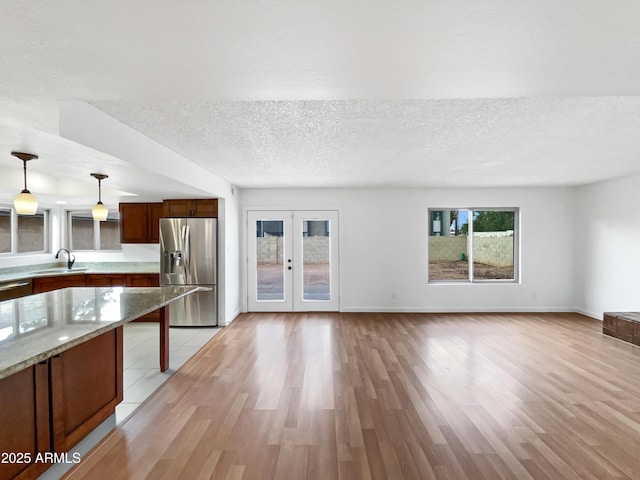 kitchen featuring a sink, stainless steel appliances, french doors, a textured ceiling, and light wood-type flooring