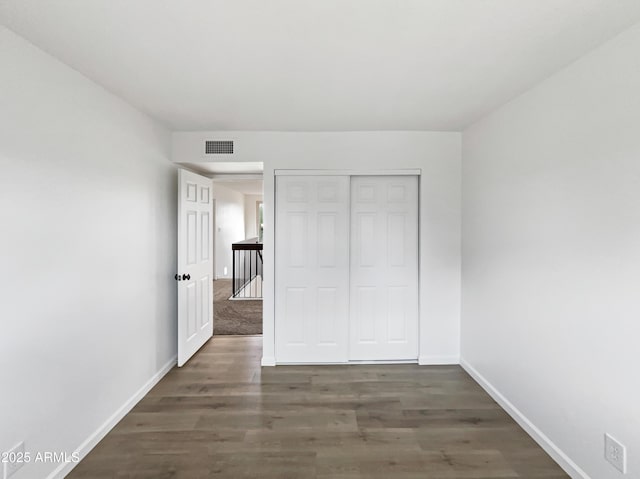 unfurnished bedroom with visible vents, baseboards, a closet, and wood finished floors