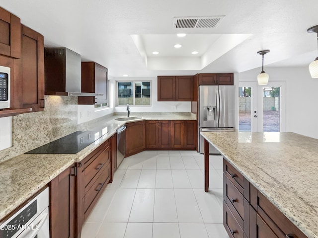 kitchen with visible vents, a sink, appliances with stainless steel finishes, a raised ceiling, and wall chimney exhaust hood