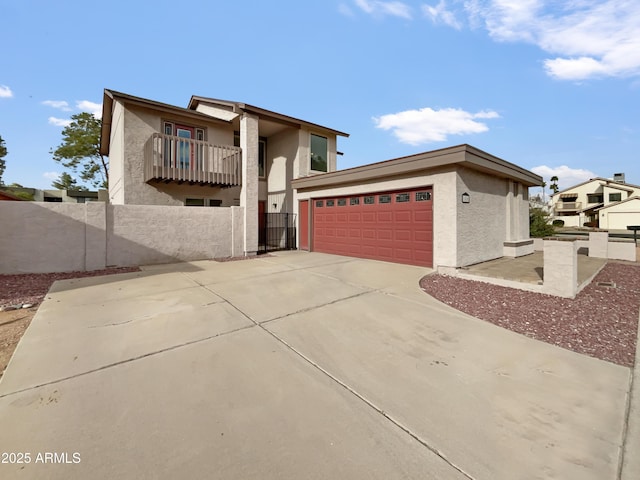 view of front of property featuring stucco siding, driveway, fence, an attached garage, and a balcony