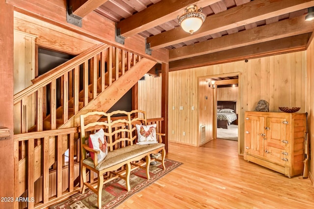 interior space featuring beamed ceiling, light wood-type flooring, wooden walls, and wood ceiling