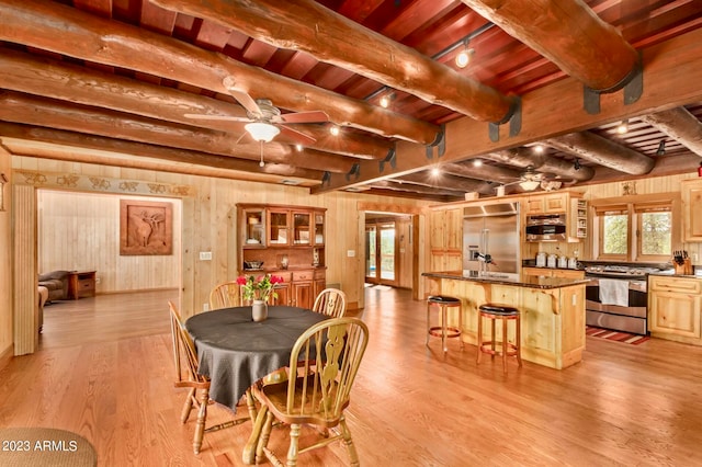 dining space with ceiling fan, beamed ceiling, wooden ceiling, and light wood-type flooring