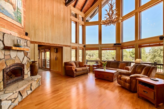 living room with a stone fireplace, high vaulted ceiling, wood ceiling, hardwood / wood-style floors, and wood walls