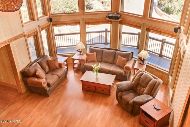 living room featuring a high ceiling, hardwood / wood-style flooring, and wooden walls