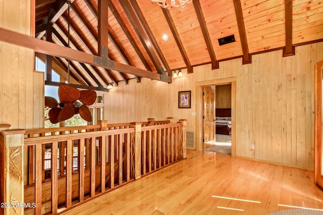 interior space with wood walls, light hardwood / wood-style flooring, beam ceiling, and wooden ceiling