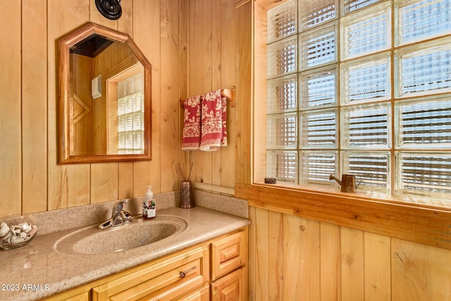 bathroom featuring wood walls, a healthy amount of sunlight, and vanity