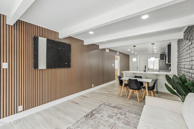 living room featuring beamed ceiling, sink, and light hardwood / wood-style flooring