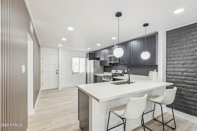 kitchen featuring pendant lighting, sink, a kitchen breakfast bar, kitchen peninsula, and stainless steel appliances