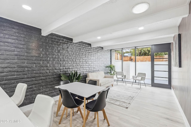 dining room featuring beamed ceiling, brick wall, and hardwood / wood-style flooring