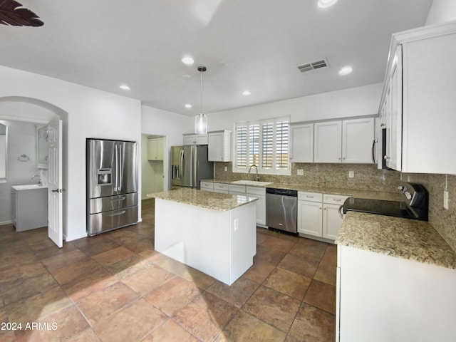 kitchen featuring white cabinetry, a center island, tasteful backsplash, pendant lighting, and appliances with stainless steel finishes