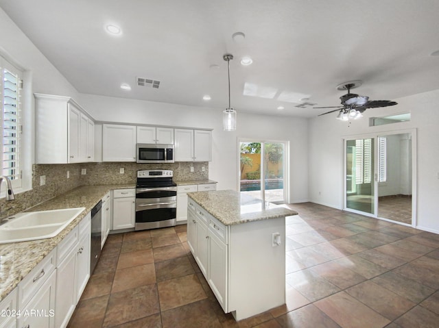 4319 E Vaughn Ave, Gilbert, AZ 85234 - kitchen with appliances with stainless steel finishes, tasteful backsplash, a kitchen island, white cabinetry, and recessed lighting