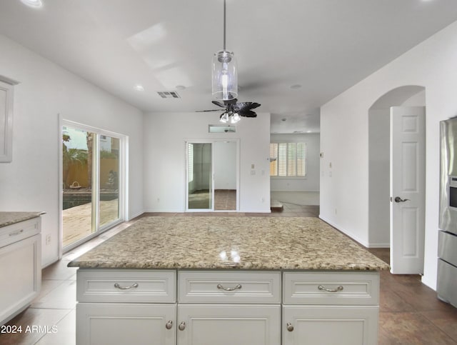 kitchen with light stone countertops, ceiling fan, and decorative light fixtures