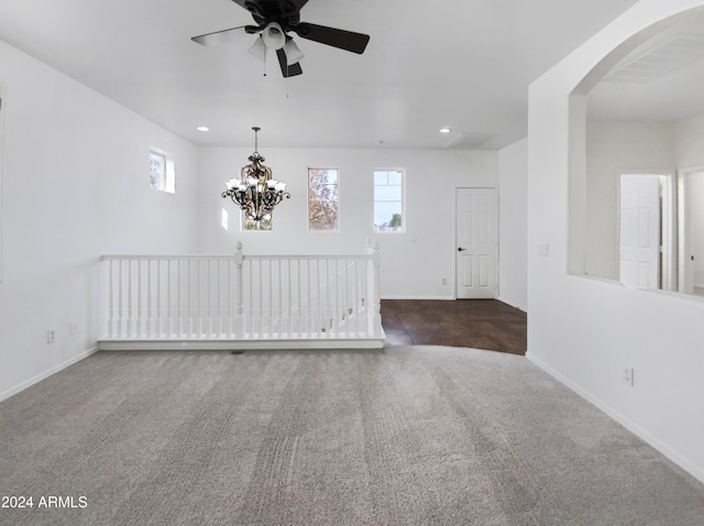 carpeted empty room featuring ceiling fan with notable chandelier