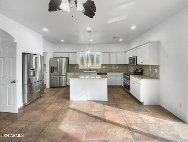 kitchen with white cabinetry, ceiling fan, a center island, stainless steel appliances, and decorative light fixtures