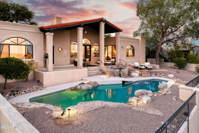 pool at dusk with a patio area