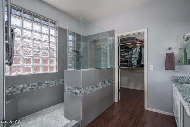 12503 W Vista Paseo Dr, Litchfield Park, AZ 85340 - bathroom with vanity, wood finished floors, baseboards, walk in shower, and a walk in closet