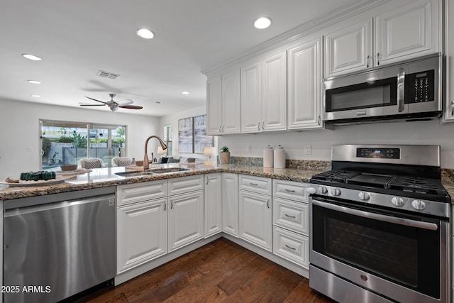 kitchen with stone counters, sink, kitchen peninsula, white cabinets, and appliances with stainless steel finishes