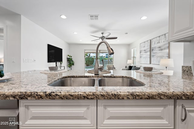 kitchen featuring ceiling fan, white cabinetry, light stone countertops, and sink