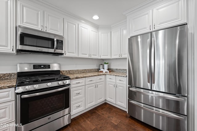 kitchen with dark stone countertops, white cabinets, dark hardwood / wood-style floors, and appliances with stainless steel finishes