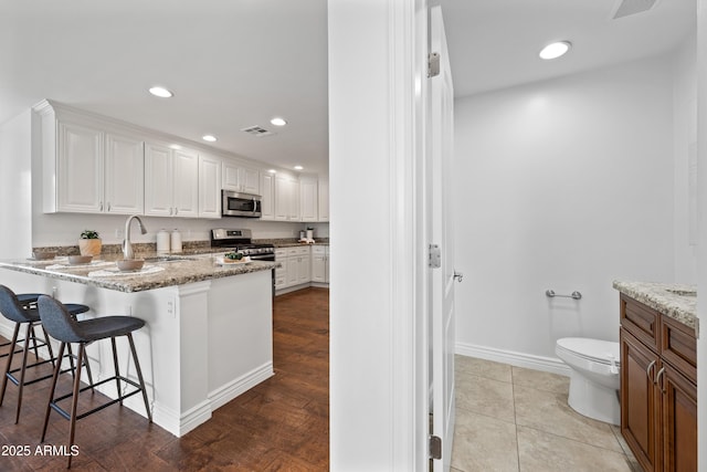 kitchen featuring white cabinets, stainless steel appliances, light stone counters, and sink