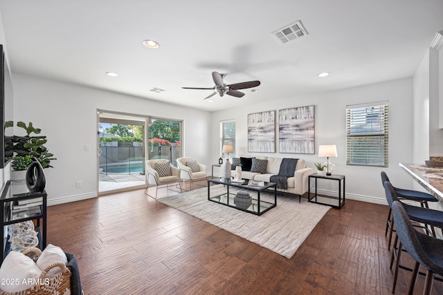 living room with dark hardwood / wood-style flooring, ceiling fan, and plenty of natural light