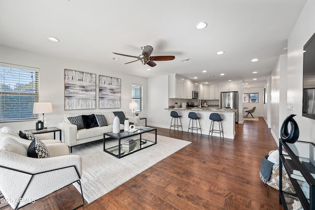 living room with ceiling fan and dark wood-type flooring