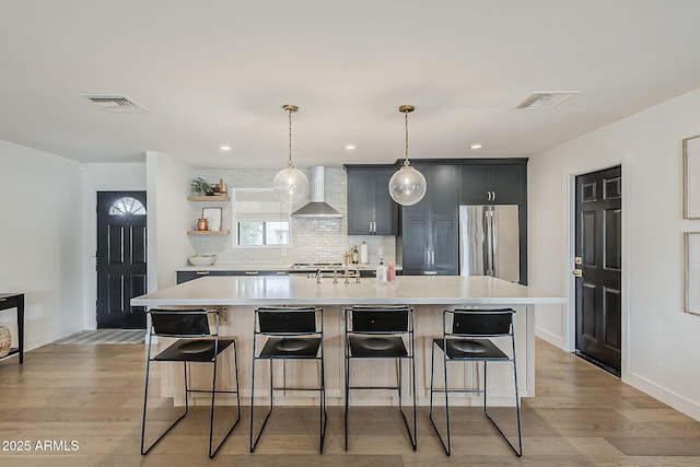 8320 E Monte Vista Rd, Scottsdale, AZ 85257 - kitchen with wall chimney exhaust hood, stainless steel fridge, open shelves, light countertops, and a kitchen bar