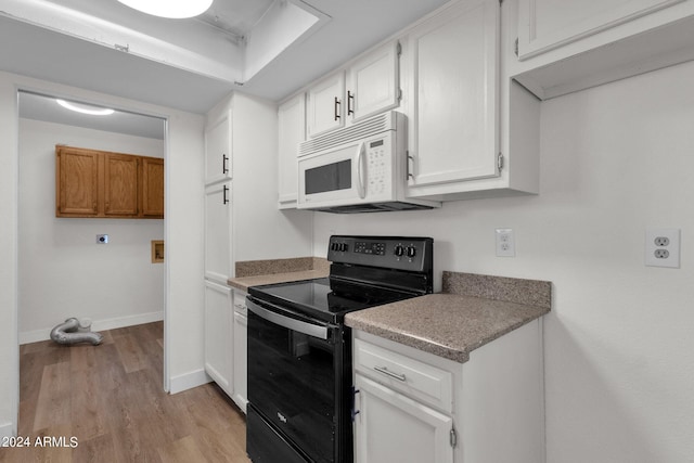 kitchen with light hardwood / wood-style flooring, white cabinets, and black / electric stove