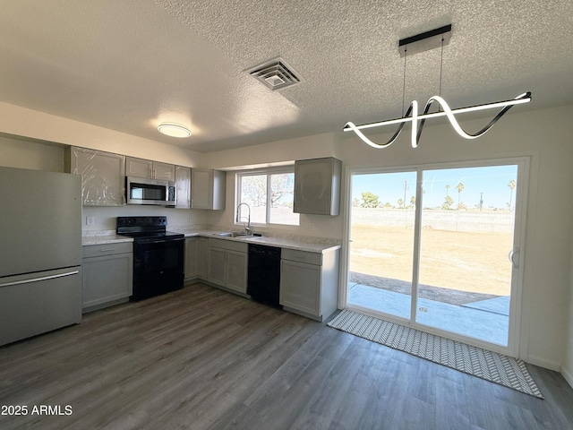 kitchen with gray cabinetry, a sink, visible vents, light countertops, and black appliances