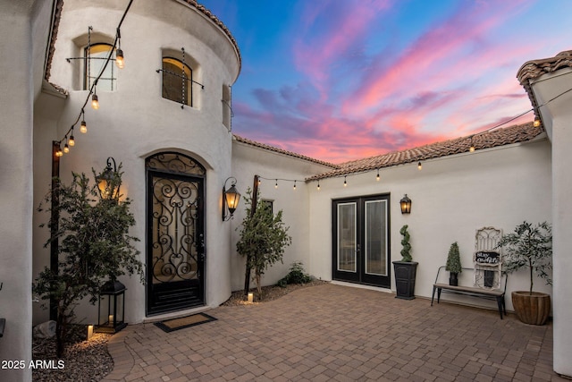 exterior entry at dusk with french doors and a patio