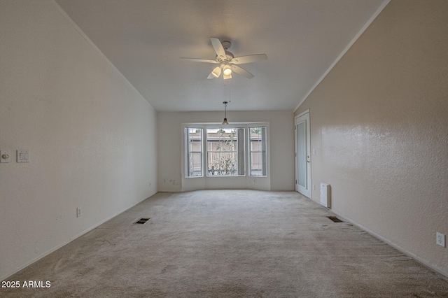 spare room featuring ceiling fan, ornamental molding, lofted ceiling, and light colored carpet