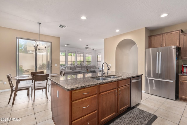 3964 E Hummingbird Ln, Phoenix, AZ 85050 - kitchen with appliances with stainless steel finishes, a sink, arched walkways, light tile patterned floors, and dark stone counters